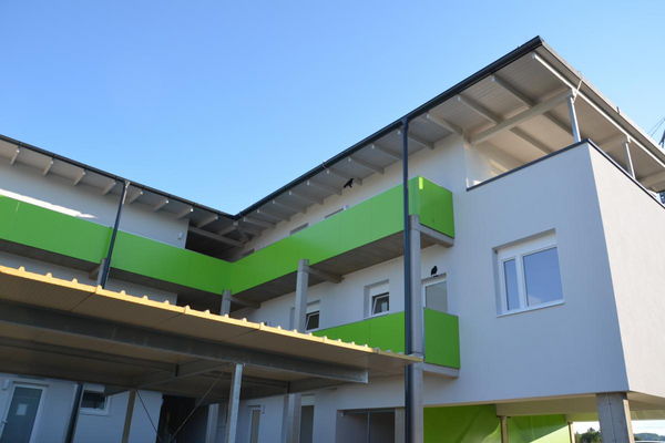 Weißes Wohngebäude mit grünen Balkonen